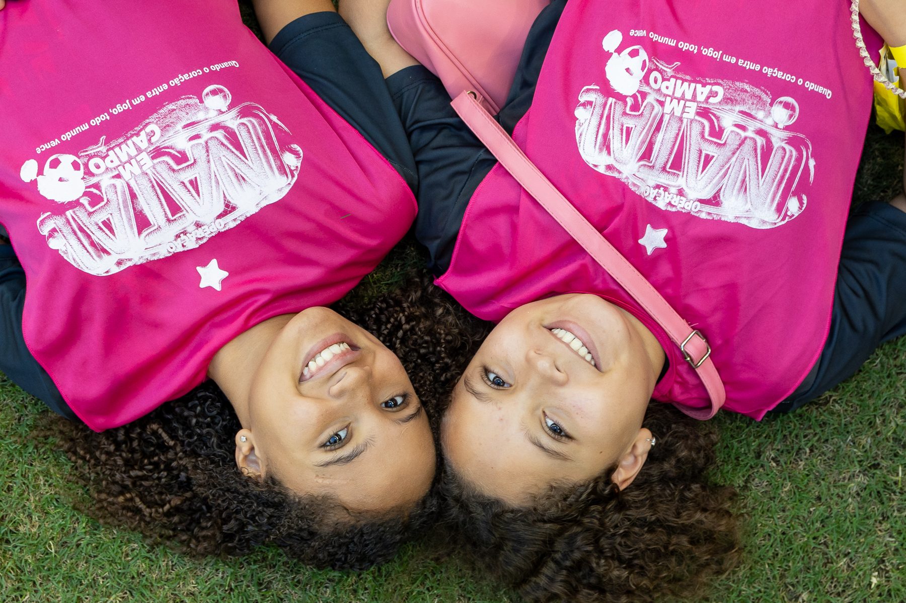 Duas crianças sorrindo deitadas com camisetas do projeto